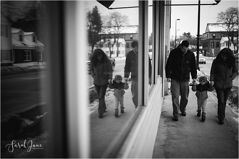 Window reflection of family walking down sidewalk Sarah Jane photography Maine