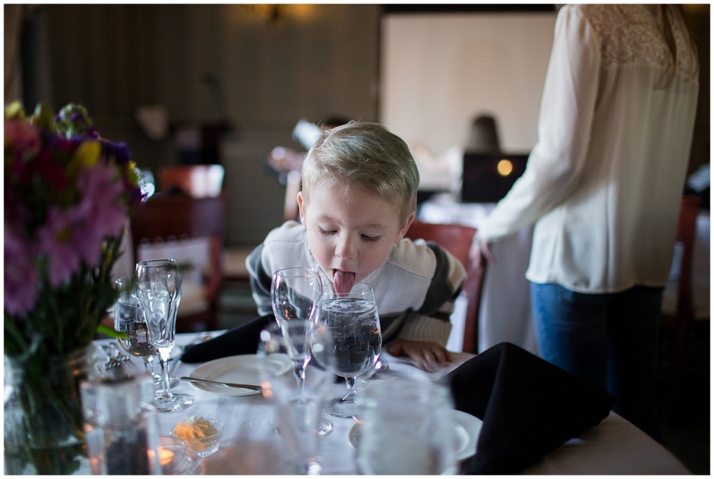 little boy sticking his tongue in a glass of water that may or may not be his water glass
